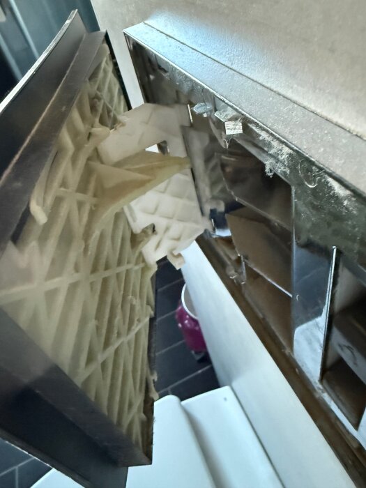 Luftfilter tas bort från en metallventil i ett hem, damm syns runt kanterna.