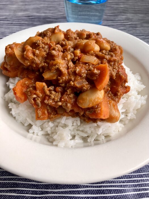 Chili con carne med bönor och morötter serverad på en tallrik med ris.