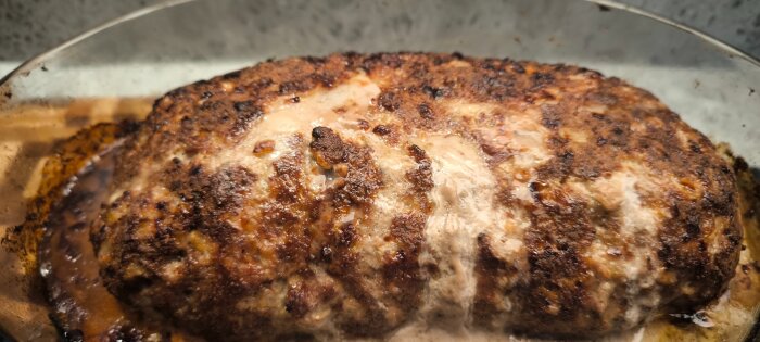 Närbild av en nygräddad köttfärslimpa med gyllenbrun och krispig yta i en ugnsform.