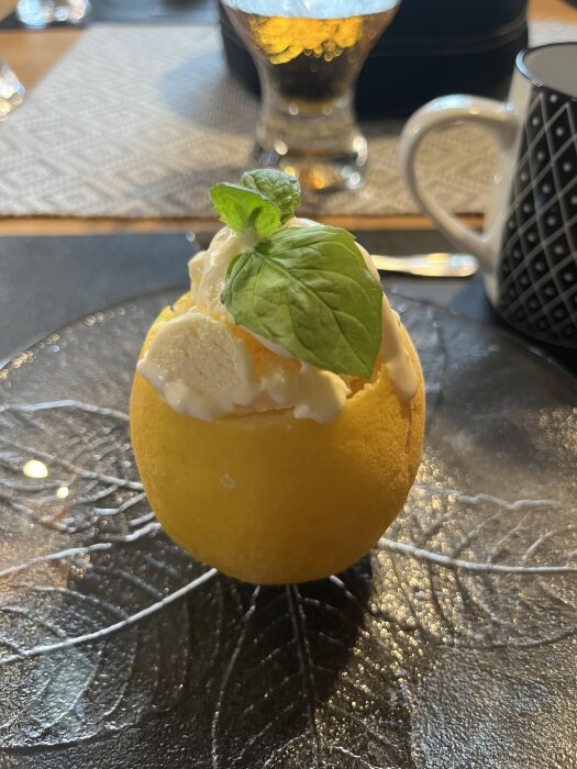 Citronglass serverad i en urholkad citron, toppad med ett grönt blad.
