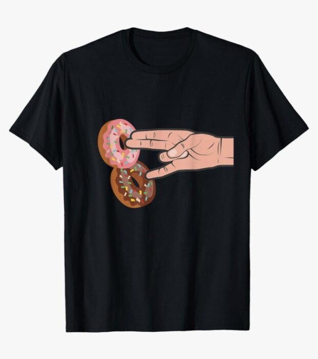 Svart t-shirt med en illustration av en hand som håller två munkar, en med rosa glasyr och en med brun glasyr, båda med strössel.
