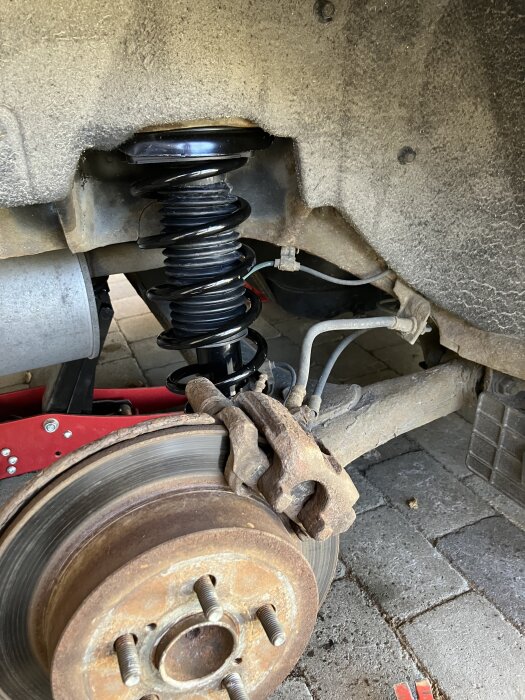 Fjäderben och bromsskiva på en Toyota Prius -07; visar nyinstallerad komponent på bakre högra sidan av bilen.