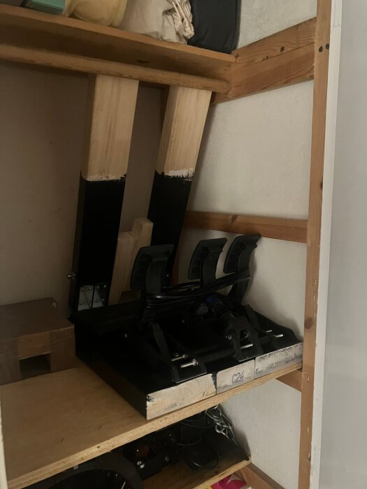 Hopfällbar träkonstruktion i en garderob med pedalmontering. Stabil design för att motstå krafter vid bromsning, delvis målad svart.