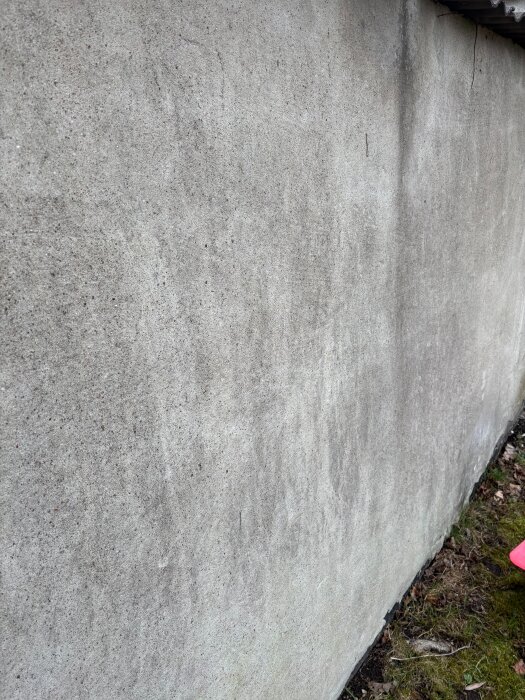 Sprucken putsad mur som behöver repareras innan målning. Visar yta och struktur på muren i dagsljus.