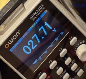 Digital multimeter som visar spänningen 27.71V.