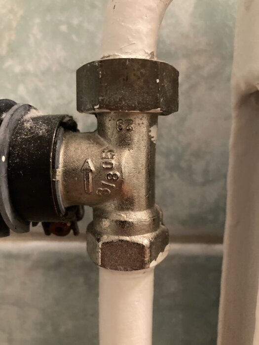Radiatorventil med märkning "3/8" och gänga, ansluten till vita rör, visas i närbild för diskussion om eventuell koppling.