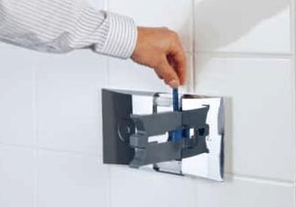 Hand justerar spolplattan vid toalettens inbyggda cistern.