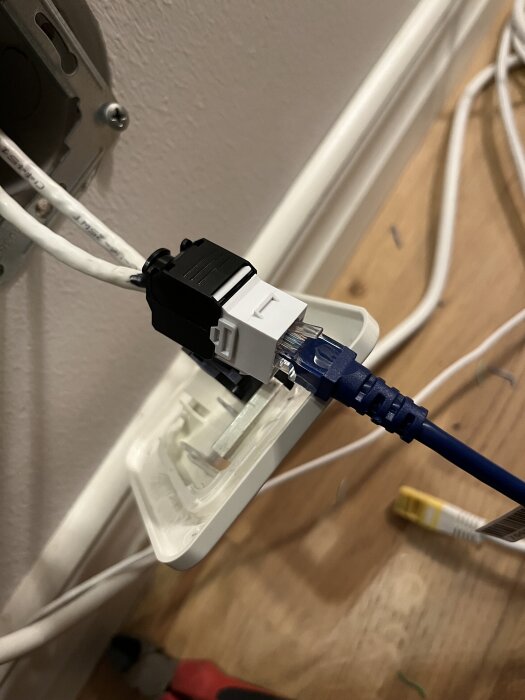 Keystone-kontakt med ansluten nätverkskabel, visar kabeldragning i hemmet.