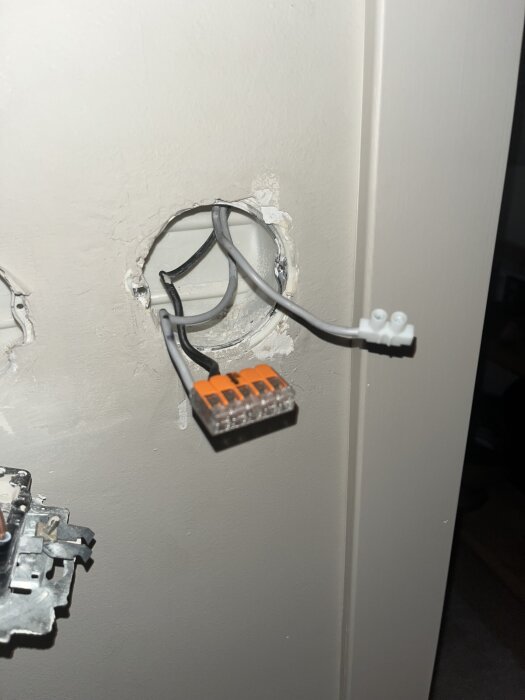 Elektriska ledningar med kopplingsplint i ett vägguttag utan lock, förberett för anslutning av elektrisk utrustning.