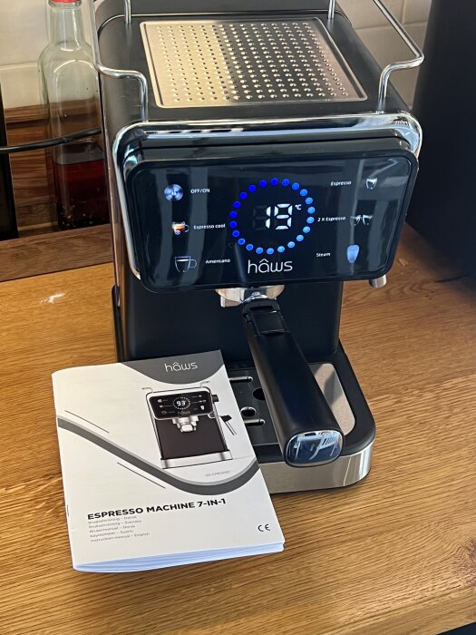 Espressomaskin höws 7-i-1 på en bänkskiva med instruktionsmanual bredvid, temperaturdisplay visar 19°C.