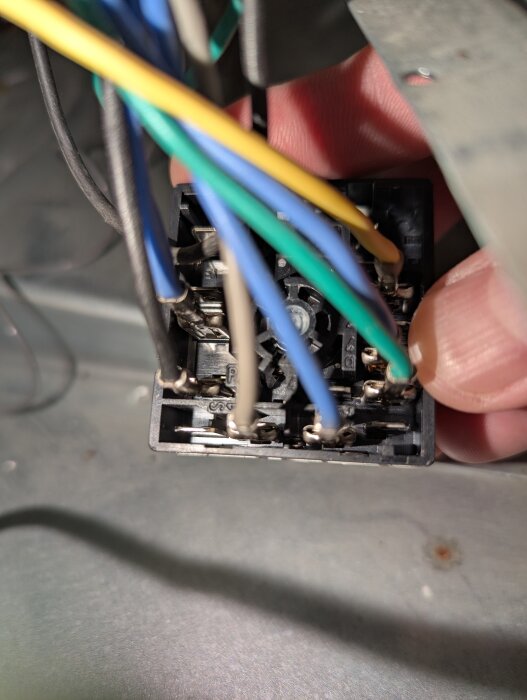 Närbild av en energiregulator med flera färgade ledningar och komponenter, installerad i en spis.