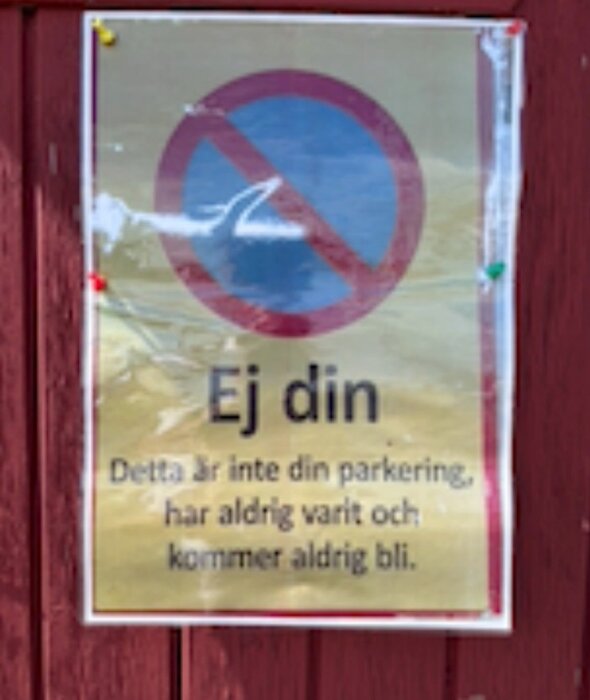 Skylt på röd vägg med texten "Ej din. Detta är inte din parkering, har aldrig varit och kommer aldrig bli" samt en bild av en bil med röd överstrykning.