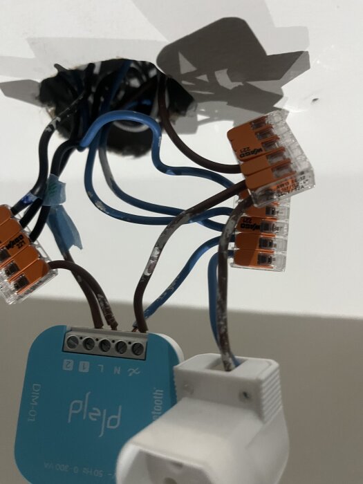 Trådlös Plejd-dimmer installerad med kopplingsklämmor och kablar monterade i en takkupa.