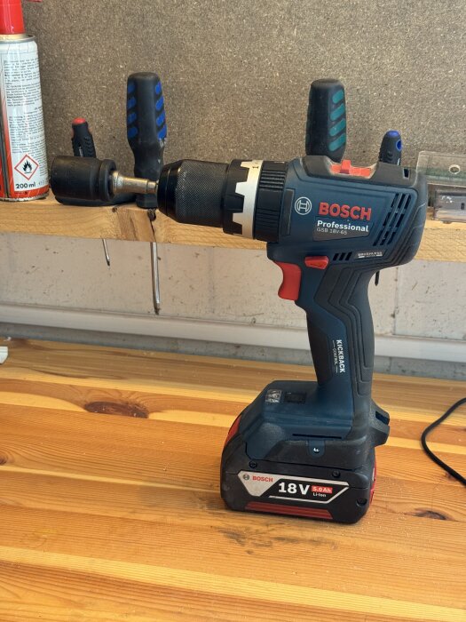 En batteridriven Bosch Professional skruvdragare med 18V Li-Ion batteri, utrustad med en 19 mm hylsa, liggande på en träbänk.
