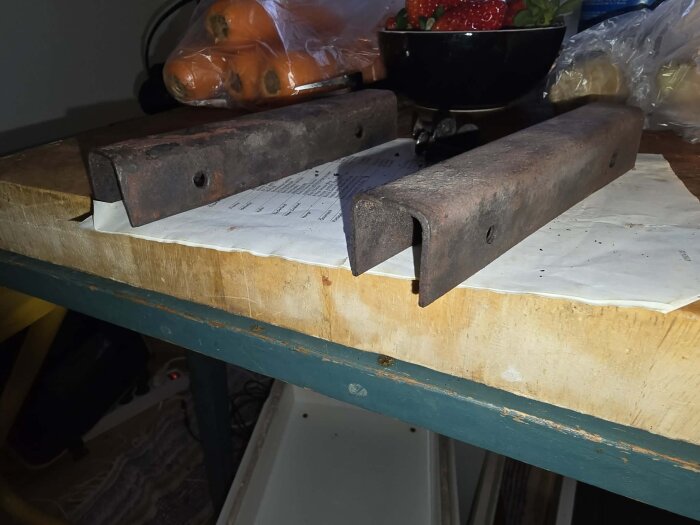 Två rostiga U-järn på ett bord, eventuellt använda till en kaminrenovering.