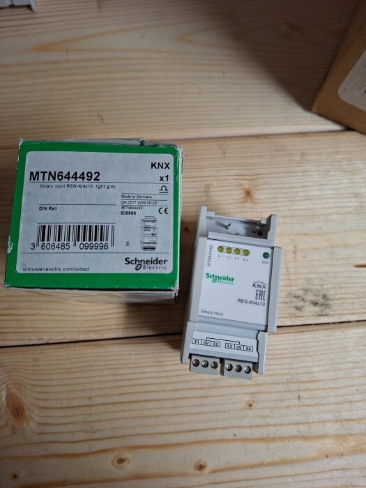 Schneider Electric KNX binäringång MTN644492 med kartong, på ett trägolv.