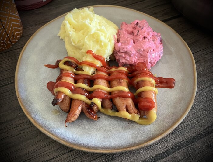 Tallrik med prinskorv med ketchup och senap, hemgjort potatismos och rödbetssallad.