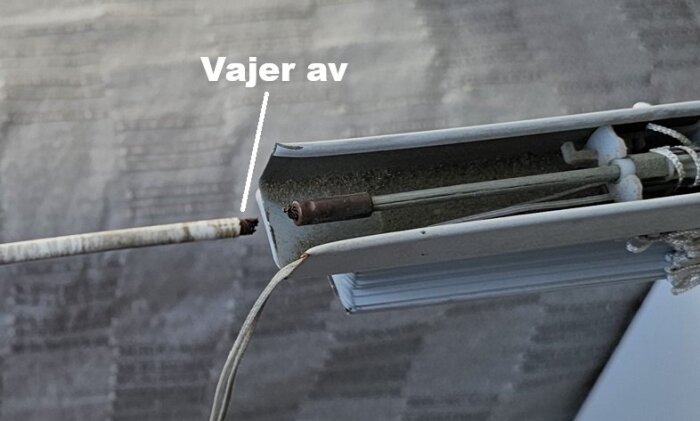 Trasig vajer i persienn, avbruten vid fästet till bärande axel, omöjlig att byta ut utan komplett demontering av konstruktionen.