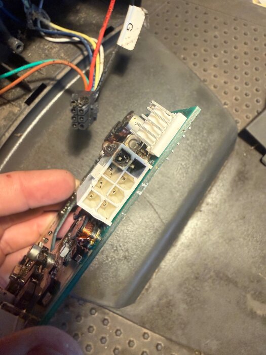 Close-up of electronic circuit board with connectors and colorful wires in the background.