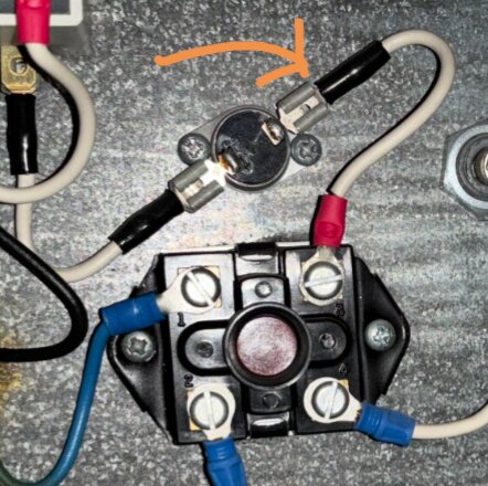Elektrisk koppling med färgmarkerade kablar och orange pil som pekar mot en specifik kabelanslutning.