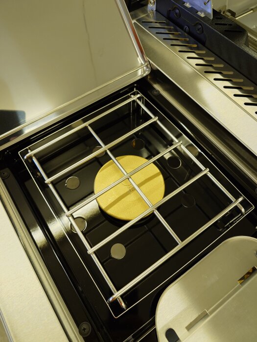 Ny gasolgrill i rostfritt stål med lock, galler och guldfärgad brännare, monterad efter en timmes arbete.