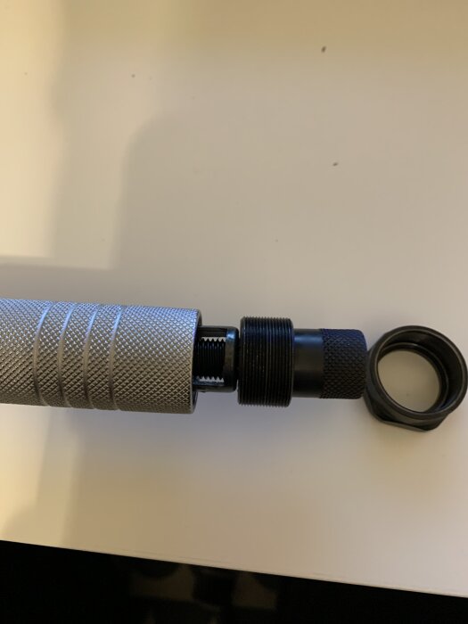 Närbild på ett silverfärgat och svart skruvverktyg med grova greppmönster på en vit bakgrund.