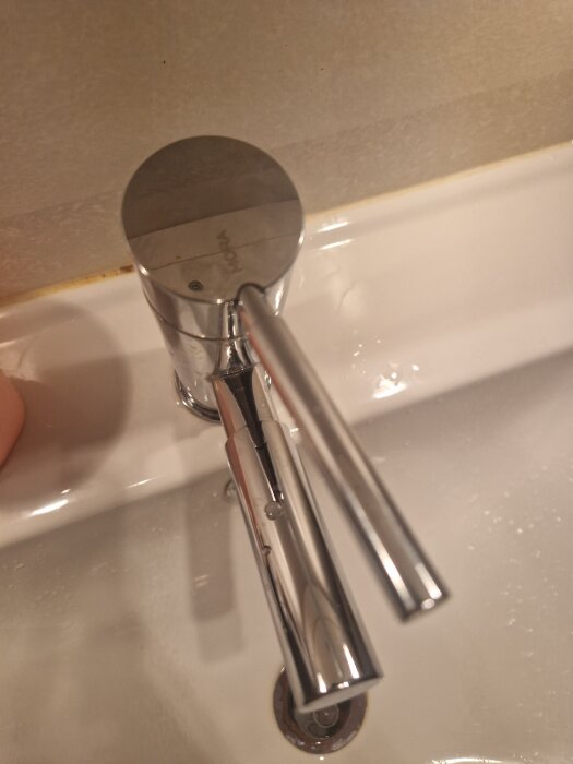 Kromfärgad Mora-blandare monterad på en vit handfat, sedd uppifrån.