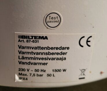 Etikett på vattenberedare från Biltema med specifikationer: 230 V, 50 Hz, 1500 W, max 7,5 bar, 50 L, IPX4. "Test passed" stämpel.