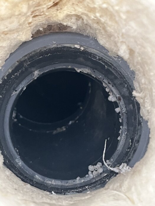 Golvbrunn efter borttagen frigolit, omgiven av materialrester. Rummet ska fallspacklas och används som tvättstuga med frånluftsvärmepump.