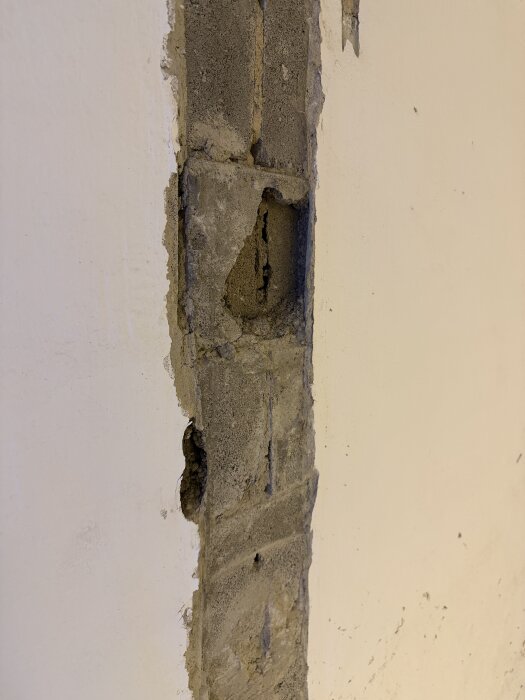 Vägg med skadat puts, djupare hål i murverket som visar behov av reparation i källarvägg.