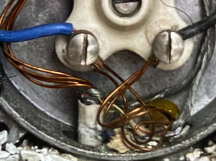 Närbild av elektriska kablar med exponerade kopparledningar i en kopplingsdosa, diskussion om lackad kabel för värmesystem.