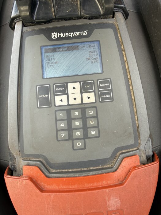 Kontrollpanel på en Husqvarna-robotgräsklippare med display som visar batteriinformation och menyer.