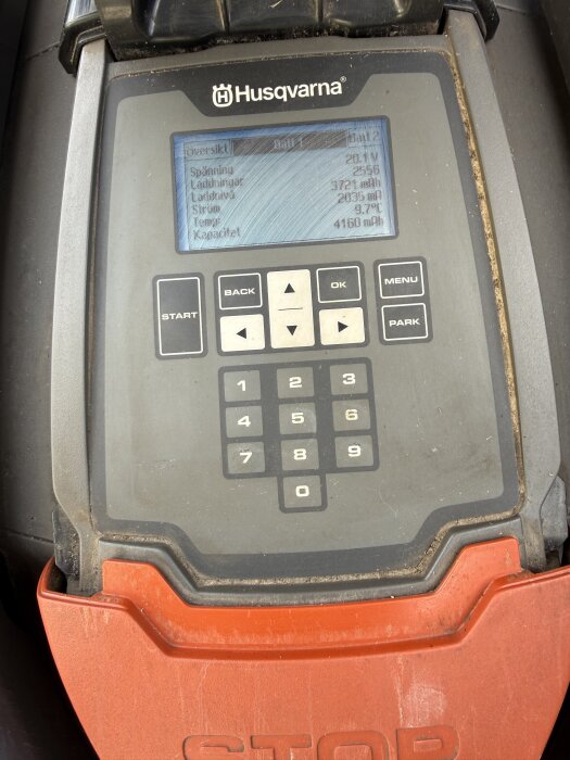 Kontrollpanel på en Husqvarna-maskin med skärm som visar batteridata och siffror på tangentbordet.