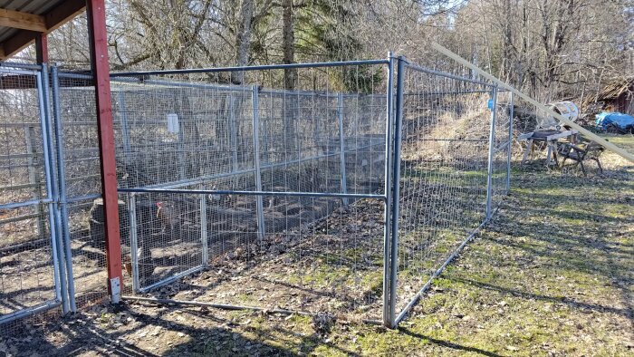 Metallbur med svetsad port för höns, belägen i trädbevuxen trädgård.