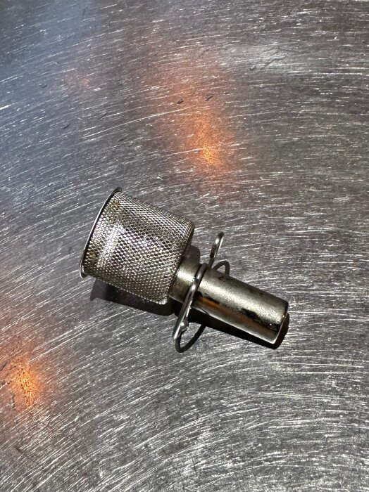 Bilden visar ett LK 522 FilterBall Magnet på en metallisk yta, med små mängder magnetit synligt.