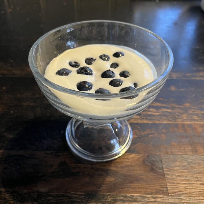 Mascarponekräm med mintbaileys och blåbär i en glasskål på ett träbord.