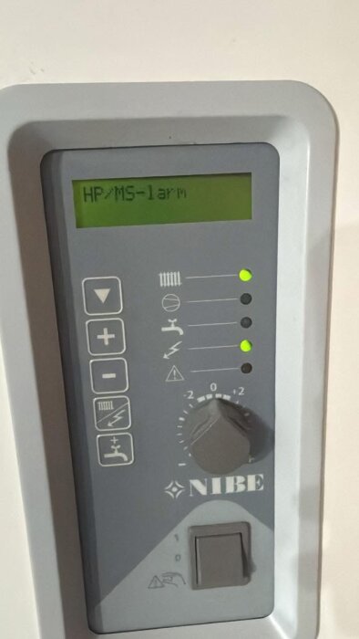 Styrpanel för NIBE värmepump med flera knappar, symboler och en digital display som visar "HP/MS-larm".