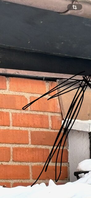 Plåt som har lossnat från en tegelfasad, pekad med streck.