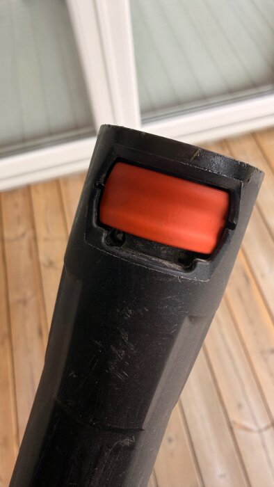Närbild av svart högtryckstvättshandtag med orange snabbfäste, del av Stihl Re130, på en altan i trä.