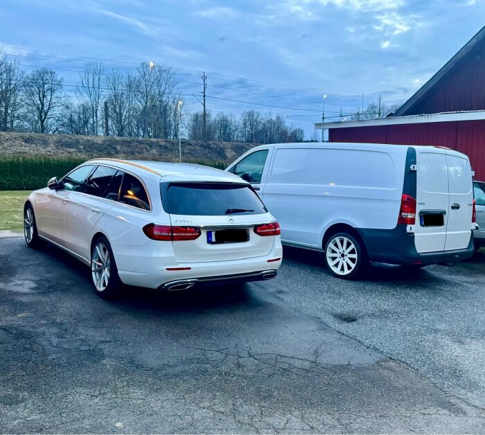 Två nytvättade bilar står parkerade, en vit kombi och en vit skåpbil, efter kvällstvätt med avfettning och snöskum, på asfalt.