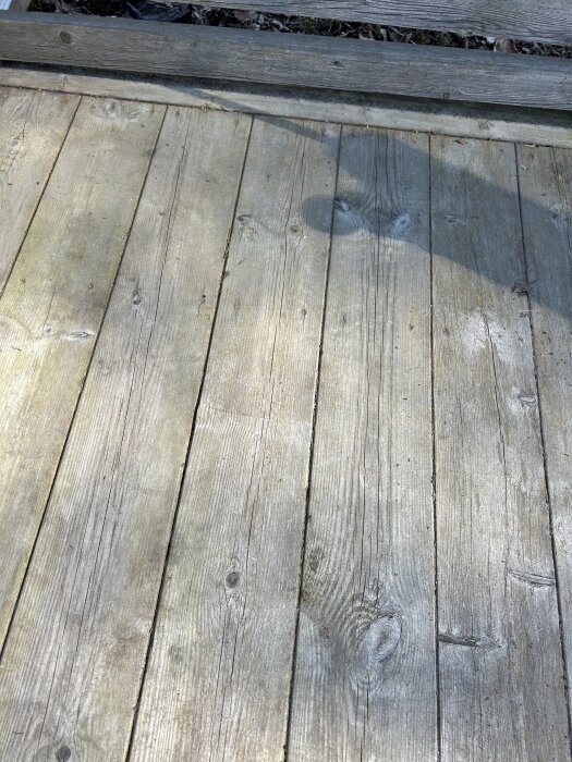 Trädäck med spår av bearbetning, visar plankor med springor och skuggor. Resultatet av att använda en sänksåg för att förbättra avrinning.