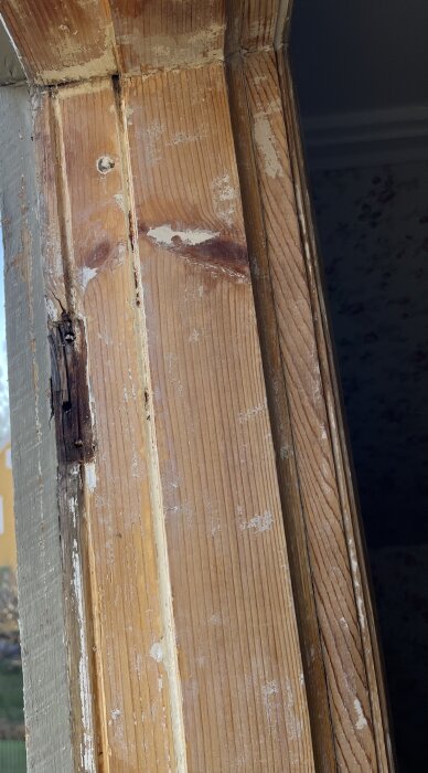 Sliten träkarm utan färg och med gamla gångjärn som visar tecken på slitage, del av fönsterrenovering.