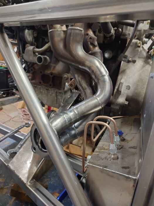 Avgassystem eller motorinstallation i pågående byggprojekt, med synliga rör och metalldelar.