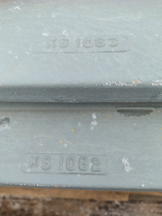 Grå målade metalluckor med texten "KS 1082" i gjutningen, har en robust och solid utformning, möjligtvis för högt tryck och temperatur.