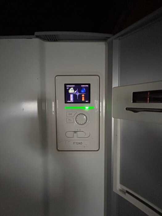 Närbild på kontrollpanelen av en NIBE F1245-12CU jordvärmepump, med skärm som visar temperaturinställningar.