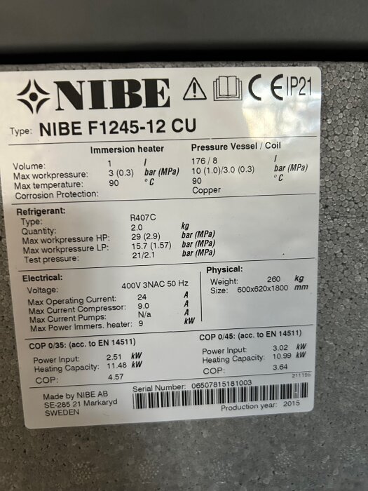 Etikett på NIBE F1245-12CU jordvärmepump med tekniska specifikationer, inklusive effekt, volym och tryckinformation. Serienummer synligt.