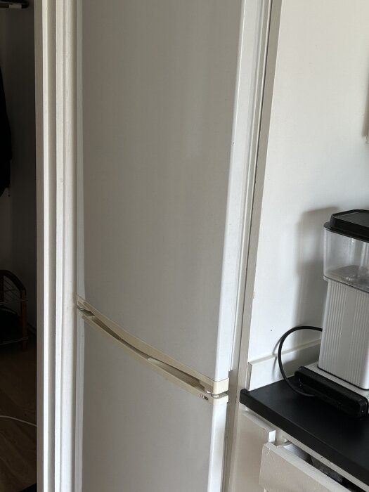 Kyl och frys trångt placerade mellan väggar, med synlig springa mot golvet.
