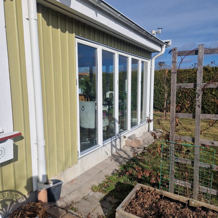 Ett vinterisolerat uterum med glaspartier i ett hus, planerat att byggas om till yttervägg med fönster.