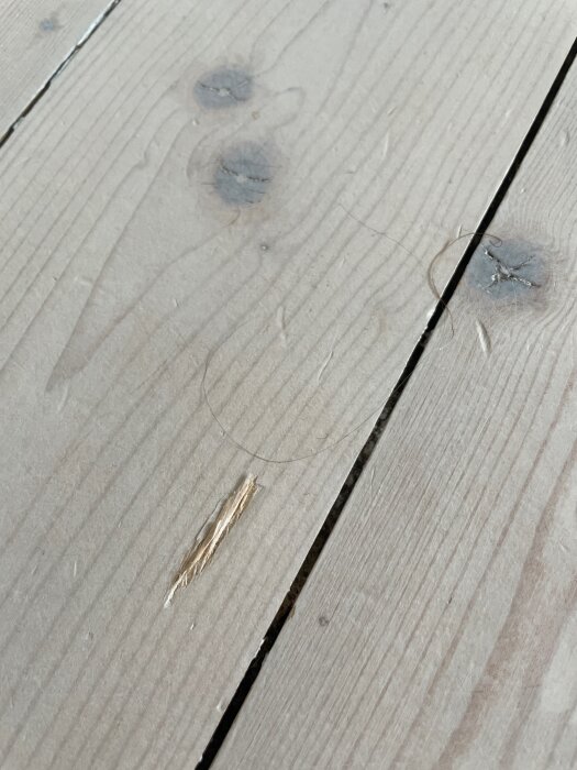 Spricka och skada på ljust trägolvbräda.