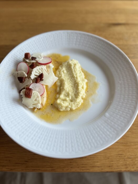 Tallrik med timjanstekt torsk, knaprig chorizo, blomkålspuré, råhyvlade rädisor och blomkål.